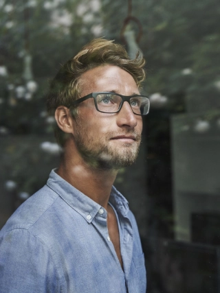 Junger Mann mit Brille schaut aus dem Fenster